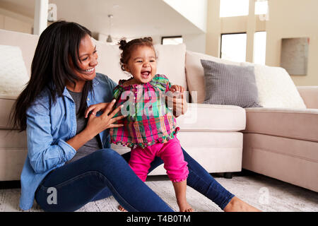 Mutter spielt mit Baby Tochter sitzen auf dem Boden der Lounge zu Hause Stockfoto