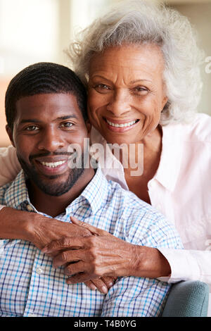 Portrait von lächelnden älteren Mutter umarmt erwachsener Sohn zu Hause Stockfoto