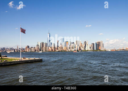 Flagge von Amerika im Wind flattern auf Ellis Island in New York unverwechselbar und iconic Manhattan Skyline im Hintergrund über den Hudson Stockfoto