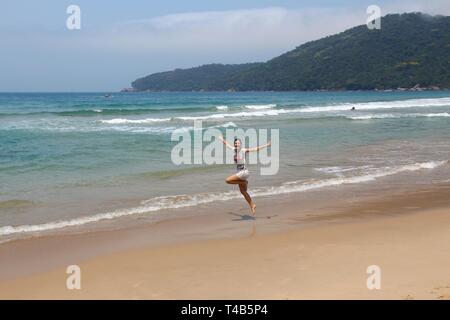 Brasilien Urlaub - glückliche Frau springen an einem Sandstrand in Rio de Janeiro. Stockfoto