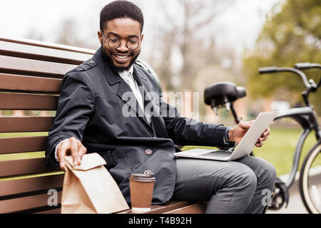 Keine Zeit für die Pause. Junge Unternehmer mit Laptop im Freien Stockfoto