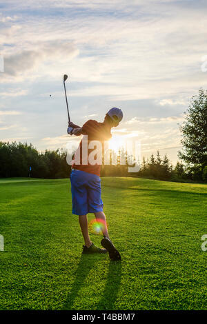 Junior Golfer spielen auf Fairway in der Abendsonne Stockfoto