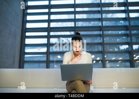 Junge student oder Geschäftsfrau, sitzen am Schreibtisch im Zimmer in einer Bibliothek oder einem Büro, mit Laptop. Stockfoto