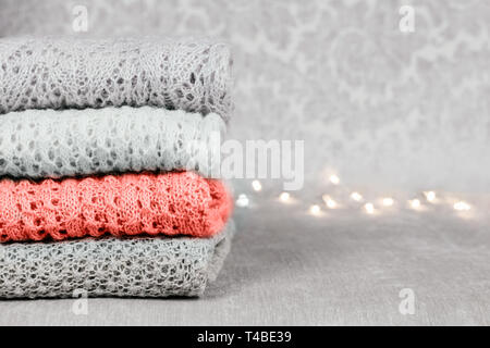 Stilvolle gestrickt, pastellfarbenen Pullover und eins in der Farbe des Jahres 2019 auf Samtigen Stoff Hintergrund stack gefaltet. Stockfoto