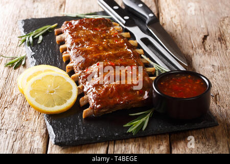 Rezept Gebratene Rippchen mit pikanter Sauce, Rosmarin und Zitrone close-up auf einem Holztisch. Horizontale Stockfoto