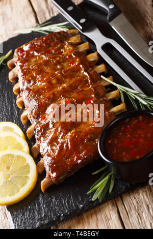 Gegrillte Schweinerippchen mit Chili Sauce und Zitrone closeup auf einer Schiefertafel Board serviert. Vertikale Stockfoto