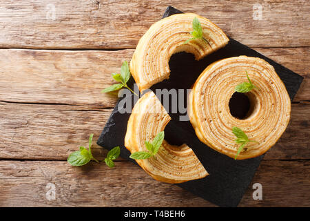 Baumkuchen, wie Baum Kuchen übersetzt, ist eine vielschichtige Schwamm Kuchen auf einen rotierenden Zylinder close-up auf dem Tisch. horizontal oben Ansicht von oben Stockfoto