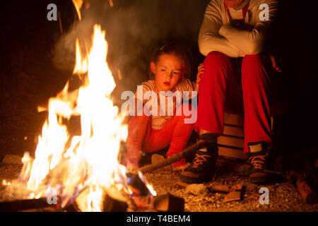 Mutter und Tochter viel Zeit mit einem selbstgemachten Lagerfeuer während abenteuerliche Campingtour, Spiel mit dem Feuer. Aktive natürliche Lebensweise, Familie Stockfoto