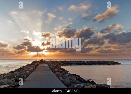Rocky Jetty/Pier bei Sonnenaufgang mit dramatischen bewölkten Himmel und Meer, Cala Bona, Mallorca, Spanien. Stockfoto