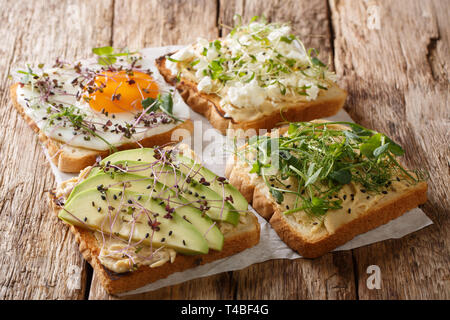 Sandwiches mit Hummus, Avocado, Fetakäse, microgreen und ei Nahaufnahme auf dem Tisch. Horizontale Stockfoto