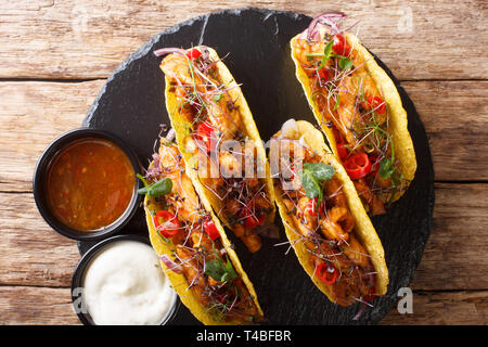 Mexikanische Tacos, gefüllt mit glasierten Huhn, microgreen und Gemüse close-up auf dem Tisch. horizontal oben Ansicht von oben Stockfoto