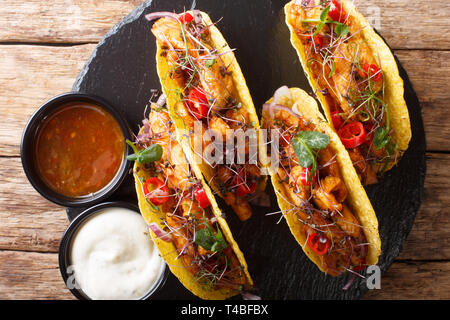 Authentische Tacos mit glasierten Huhn, microgreen und Gemüse sind mit Saucen in der Nähe serviert auf einem Schiefer Board auf dem Tisch. horizontal oben Blick von Stockfoto