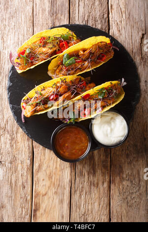 Lecker gefüllte Tacos mit glasierten Huhn, microgreen und Gemüse mit Saucen in der Nähe serviert auf einem Schiefer Board auf dem Tisch. Senkrechte Draufsicht fr Stockfoto