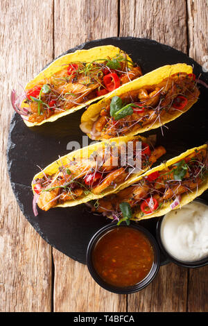 Mexikanische Tacos, gefüllt mit glasierten Huhn, microgreen und Gemüse close-up auf den Tisch. Vertikal oben Ansicht von oben Stockfoto