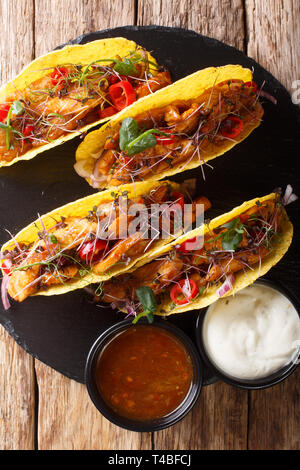 Authentische Tacos mit glasierten Huhn, microgreen und Gemüse sind mit Saucen in der Nähe serviert auf einem Schiefer Board auf dem Tisch. Vertikal oben Ansicht aus einem Stockfoto