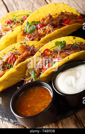 Mexikanische Tacos, gefüllt mit glasierten Huhn, microgreen und Gemüse close-up auf dem Tisch. Vertikale Stockfoto