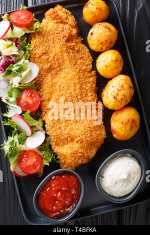 Teil von weißfischfilet in Panade mit neuen Kartoffeln und frischem Gemüse Salat close-up auf einem Teller auf den Tisch. Vertikal oben Ansicht von oben Stockfoto