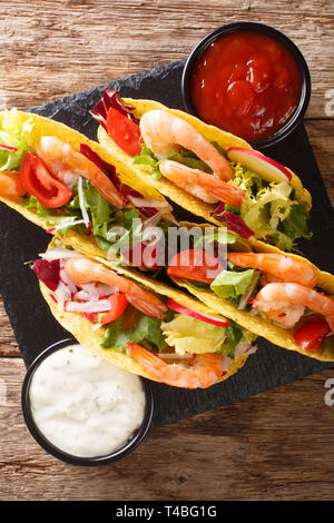 Mexikanischen fast food Tacos mit Garnelen, frisches Gemüse und Saucen close-up auf den Tisch. Vertikal oben Ansicht von oben Stockfoto