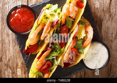 Köstliche Mexikanische Tacos mit Garnelen und Gemüse close-up auf den Tisch serviert mit Saucen. horizontal oben Ansicht von oben Stockfoto