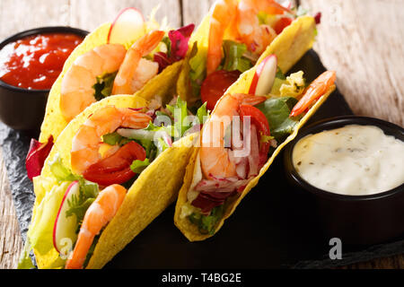 Knusprige mais Tacos mit Meeresfrüchten frisch Gemüse und Saucen close-up auf dem Tisch. Horizontale Stockfoto