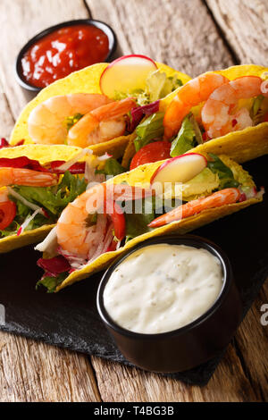 Mais Tacos mit Garnelen, frisches Gemüse und Saucen close-up auf dem Tisch. Vertikale Stockfoto