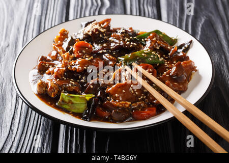 Asiatischen Hauptgericht von Schweinebraten mit mun Pilzen und Gemüse in pikanter Soße closeup auf einem Teller auf den Tisch. Horizontale Stockfoto