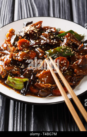 Chinesisch Leckere Pfannengerichte vom Schwein mit mun Pilzen und Gemüse close-up auf einem Teller auf den Tisch. Vertikale Stockfoto