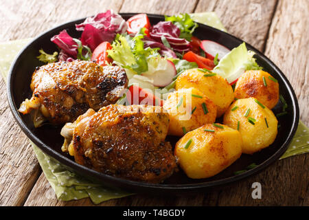 Volles Abendessen Hähnchen Schenkel mit neuen Kartoffeln und frischem Salat close-up auf einem Teller auf den Tisch. Horizontale Stockfoto
