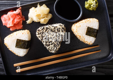 Onigiri in Sesam mit Ingwer, Wasabi und Sauce in der Nähe serviert auf einem Teller auf den Tisch. horizontal oben Ansicht von oben Stockfoto