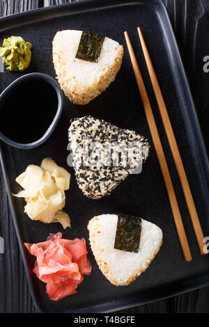 Onigiri in Sesam mit Ingwer, Wasabi und Sauce in der Nähe serviert auf einem Teller auf den Tisch. Vertikal oben Ansicht von oben Stockfoto