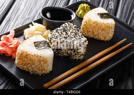 Onigiri in Sesam mit Ingwer, Wasabi und Sauce in der Nähe serviert auf einem Teller auf den Tisch. Horizontale Stockfoto