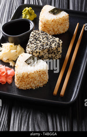 Köstliche japanische onigiri Snack serviert mit Ingwer, Wasabi und Sauce close-up auf einem Teller auf den Tisch. Vertikale Stockfoto