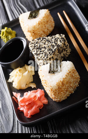 Japanische onigiri serviert mit Ingwer, Wasabi und Sauce close-up auf einem Teller auf den Tisch. Vertikale Stockfoto
