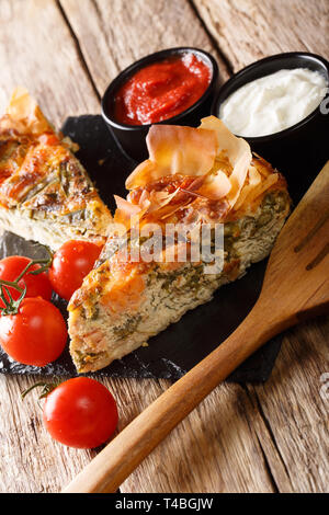 In Scheiben geschnitten Quiche gefüllt mit Lachs, Tomaten, Käse und Kräutern close-up auf dem Tisch. Vertikale Stockfoto