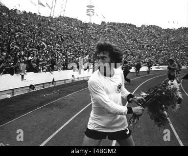 Deutsche Mittelfeldspieler Paul Breitner, der normalerweise für Bayern München spielt, jubelnde wirft einen Blumenstrauß in die Menge. Die deutsche Nationalmannschaft gewinnt das WM-Finale gegen die Niederlande am 7. Juli 1974 vor 80.000 Zuschauern im Münchner Olympiastadion mit einem Endstand von 2-1 und gewinnt die WM-Titel zum zweiten Mal. | Verwendung weltweit Stockfoto