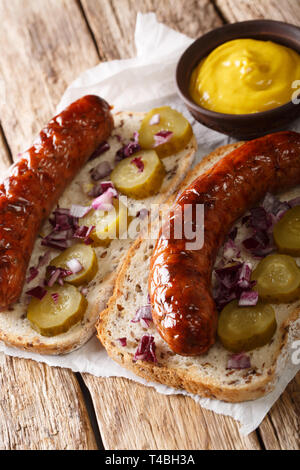 Sandwiches mit gegrillten Würstchen, Gewürzgurken, Zwiebeln und Senf close-up auf die Tabelle öffnen. Vertikale Stockfoto