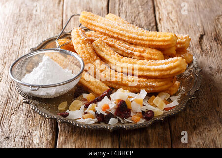 Churros sind ein frittiertes Gebäck, dass Zucker gerollt werden und serviert mit kandierten Früchten close-up auf einem Teller auf den Tisch. Horizontale Stockfoto