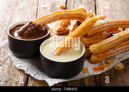 Frisch heiß Churros mit heißer Schokolade und Kondensmilch close-up, auf dem Tisch. Horizontale Stockfoto