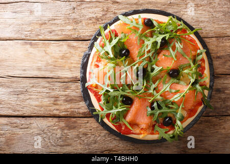 Rezept für köstliche italienische Pizza mit Lachs und Rucola, schwarze Oliven und Mozzarella close-up auf dem Tisch. horizontal oben Ansicht von oben Stockfoto