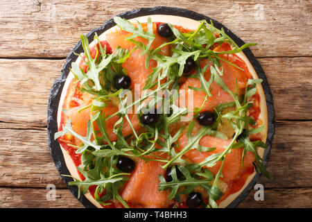 Leckere Pizza mit gesalzenen Lachs, Rucola, Oliven und Käse Nahaufnahme auf dem Tisch. horizontal oben Ansicht von oben Stockfoto