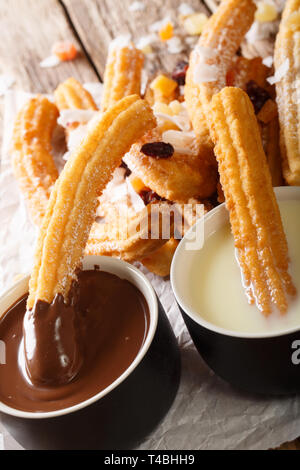 Frittierte süße Churros serviert mit heißer Schokolade und Kondensmilch close-up auf dem Tisch. Vertikale Stockfoto