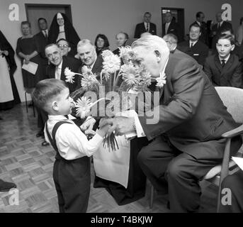 Bundeskanzler Ludwig Erhard besuche Waisen in einem Waisenhaus in Bonn am 20. Dezember 1963, sie mit Geschenken zu überraschen. Das Bild zeigt die Ludwig Erhard, der von einem kleinen Jungen mit einem Blumenstrauß begrüßt wird. | Verwendung weltweit Stockfoto