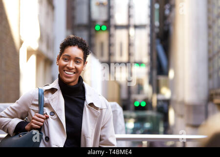 Nahaufnahme einer tausendjährigen schwarz Geschäftsfrau auf einer Straße in London stand lächelnd in die Kamera, Taille bis Stockfoto