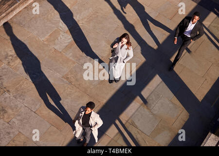 Luftaufnahme von drei Geschäftsleute gehen in die gleiche Richtung an einem sonnigen Urban Street, horizontal Stockfoto