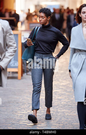 Junge schwarze Geschäftsfrau zu Fuß auf der Straße in London mit Smartphone, selektiver Fokus Stockfoto