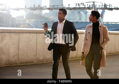 Zwei Kollegen wandern an der Themse Riverside in London sprechen, man Gestik Stockfoto