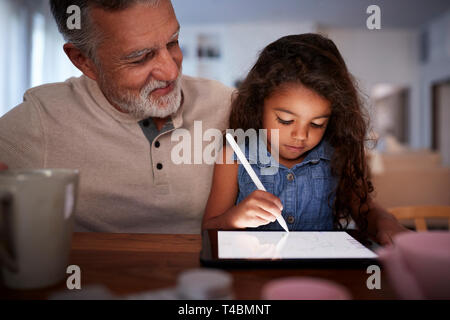 Senior Hispanic Mann mit seiner jungen Enkelin mit Stift und Tablet Computer, front, Nahaufnahme Stockfoto