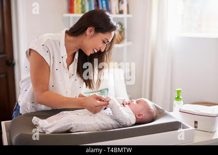 Glückliche Mutter Wechseln der Windel ihres neugeborenen Sohn zu Hause auf einen Wickeltisch, Taille bis Stockfoto