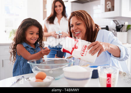 Junge Mädchen, die einen Kuchen in der Küche mit ihrer Großmutter, Mutter steht, selektiven Fokus Stockfoto