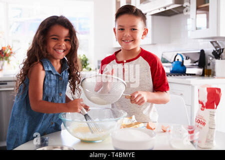 Bruder und Schwester Vorbereitung Kuchenteig gemeinsam am Küchentisch auf Kamera, Taille bis Stockfoto